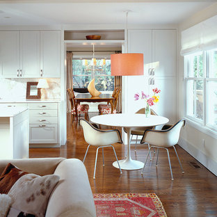 Imagen de comedor de estilo americano, abierto, con paredes blancas y suelo de madera oscura