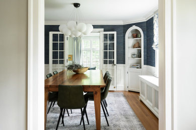 Aménagement d'une salle à manger classique fermée avec un mur bleu, un sol en bois brun, du papier peint, boiseries et un sol marron.