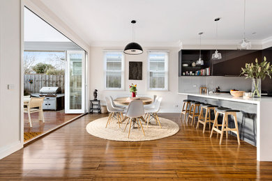 Idée de décoration pour une salle à manger ouverte sur la cuisine design de taille moyenne avec un sol en bois brun et un mur beige.