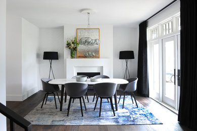 Idée de décoration pour une salle à manger design avec un mur blanc, parquet foncé, une cheminée standard et un sol marron.