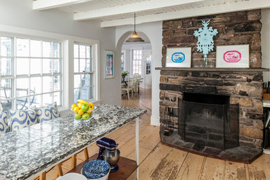 Example of a mid-sized farmhouse medium tone wood floor dining room design in New York with beige walls, a standard fireplace and a stone fireplace