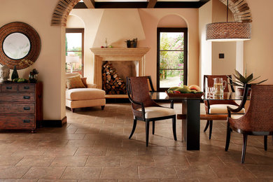 На фото: кухня-столовая среднего размера в стиле неоклассика (современная классика) с коричневыми стенами, полом из керамогранита, стандартным камином, фасадом камина из камня и коричневым полом