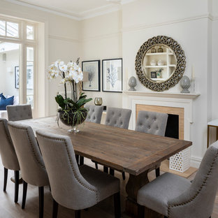 Design ideas for a medium sized classic enclosed dining room in London with beige walls, light hardwood flooring and a standard fireplace.