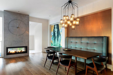 Idée de décoration pour une grande salle à manger design avec un mur blanc, un sol en bois brun, une cheminée ribbon, un manteau de cheminée en béton et un sol marron.