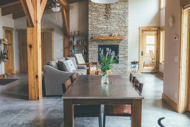 Large mountain style concrete floor and gray floor enclosed dining room photo in Other with beige walls, a standard fireplace and a stone fireplace