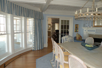 Example of a large beach style medium tone wood floor and brown floor enclosed dining room design in New York with blue walls, a corner fireplace and a wood fireplace surround