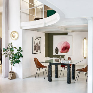 Immagine di una sala da pranzo aperta verso il soggiorno minimal con pareti bianche, pavimento in cemento e pavimento grigio