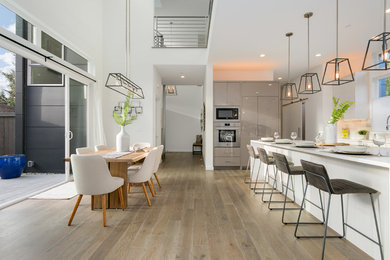 Ejemplo de comedor de cocina moderno de tamaño medio sin chimenea con paredes blancas, suelo de madera en tonos medios y suelo marrón