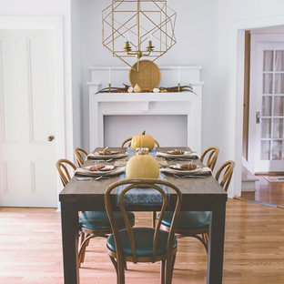 Diseño de comedor de estilo americano con paredes blancas, suelo de madera clara, chimenea tradicional y marco de chimenea de madera