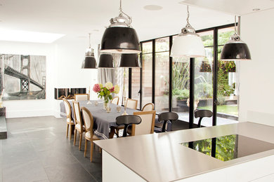 Large contemporary kitchen/dining room in London with white walls, grey floors and a corner fireplace.