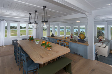Cette image montre une grande salle à manger ouverte sur la cuisine craftsman avec un mur blanc, parquet clair, aucune cheminée et un sol marron.