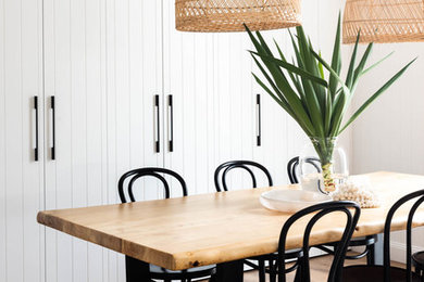 This is an example of a coastal dining room in Brisbane with white walls, medium hardwood flooring and brown floors.