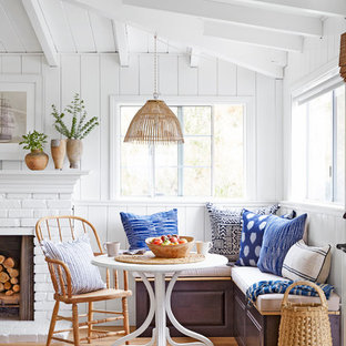 Small nautical dining room in Los Angeles with white walls, light hardwood flooring, a standard fireplace and a brick fireplace surround.