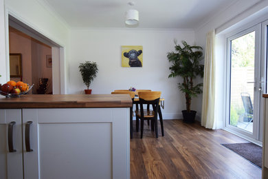Modelo de comedor de cocina clásico grande con paredes blancas, suelo laminado y suelo marrón