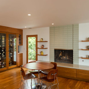 Inspiration pour une salle à manger ouverte sur la cuisine minimaliste de taille moyenne avec un manteau de cheminée en béton, un mur blanc, un sol en bois foncé, une cheminée standard et un sol marron.