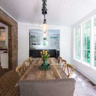 Idée de décoration pour une salle à manger tradition avec un sol en brique et un mur blanc.