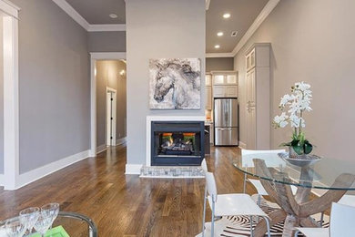 This is an example of a medium sized traditional open plan dining room in Nashville with grey walls, light hardwood flooring, a two-sided fireplace and a metal fireplace surround.