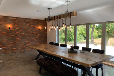 Open plan dining room in Sussex with grey floors and brick walls.