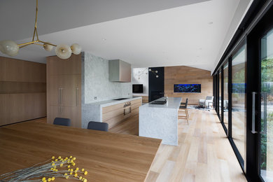 Cette photo montre une grande salle à manger ouverte sur la cuisine moderne avec un mur gris.
