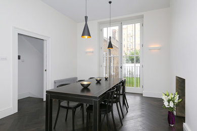 Inspiration pour une salle à manger ouverte sur le salon design de taille moyenne avec un mur blanc, un sol en bois brun, une cheminée standard et un sol marron.