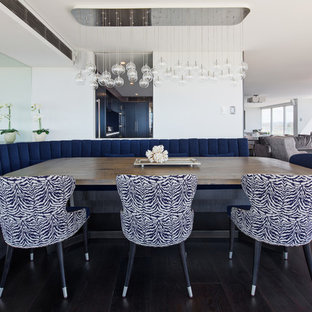 Modelo de comedor costero, grande, abierto, con paredes blancas, suelo de madera oscura y suelo negro