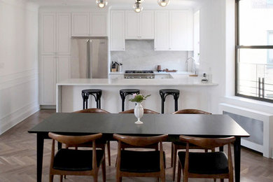 На фото: кухня-столовая в стиле неоклассика (современная классика) с белыми стенами и темным паркетным полом с