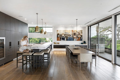 Idee per una grande sala da pranzo aperta verso la cucina design con pareti bianche, pavimento in legno massello medio e pavimento marrone