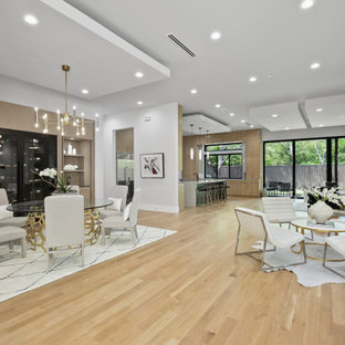 Réalisation d'une grand salle à manger ouverte sur la cuisine minimaliste avec un mur blanc, un sol en bois clair, aucune cheminée et un sol jaune.