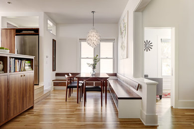 На фото: кухня-столовая в стиле модернизм с белыми стенами и паркетным полом среднего тона