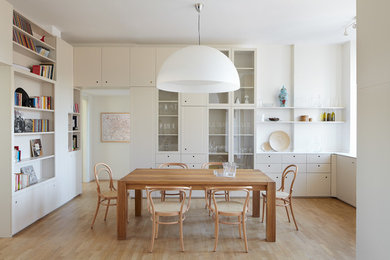 Imagen de comedor contemporáneo con paredes blancas y suelo de madera clara
