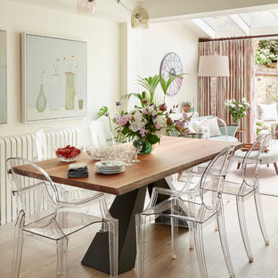 Photo of a mid-sized eclectic open plan dining in London with beige walls and light hardwood floors.