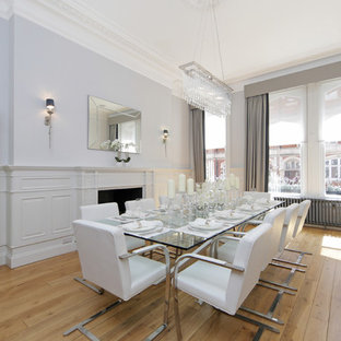 Design ideas for a medium sized traditional enclosed dining room in London with light hardwood flooring, a standard fireplace, beige floors and grey walls.