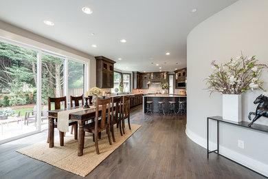 Cette photo montre une grande salle à manger ouverte sur la cuisine chic avec parquet foncé, un mur blanc et aucune cheminée.