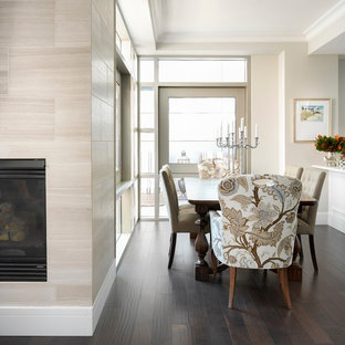 Immagine di una piccola sala da pranzo aperta verso la cucina classica con pareti beige, parquet scuro, camino sospeso, cornice del camino piastrellata e pavimento marrone
