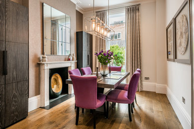 Photo of a classic dining room in London with beige walls, dark hardwood flooring, a standard fireplace, brown floors and a chimney breast.