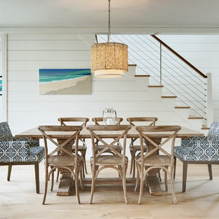 Imagen de comedor costero con paredes blancas, suelo de madera clara y suelo beige