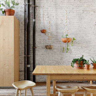 Esempio di una grande sala da pranzo aperta verso la cucina industriale con pareti bianche, pavimento in legno massello medio, camino classico, cornice del camino in legno e pavimento marrone