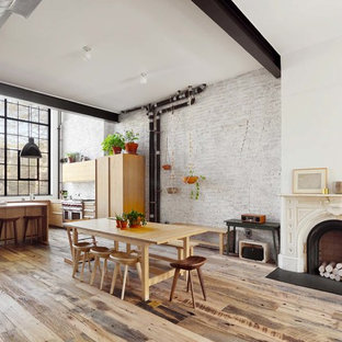 Example of a large urban medium tone wood floor and brown floor kitchen/dining room combo design in New York with white walls, a standard fireplace and a wood fireplace surround