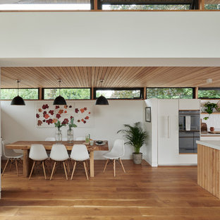 Design ideas for a medium sized contemporary open plan dining room in Cambridgeshire with medium hardwood flooring, white walls and beige floors.