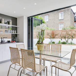 This is an example of a contemporary kitchen/dining room in London with white walls, no fireplace and white floors.