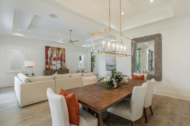 Immagine di una grande sala da pranzo aperta verso la cucina stile marinaro con pareti bianche, parquet chiaro e nessun camino