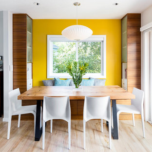 Immagine di una sala da pranzo aperta verso il soggiorno minimal di medie dimensioni con pareti gialle, parquet chiaro e nessun camino
