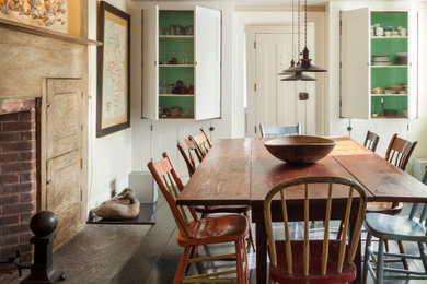 Example of a farmhouse dark wood floor and brown floor dining room design in New York with white walls and a standard fireplace
