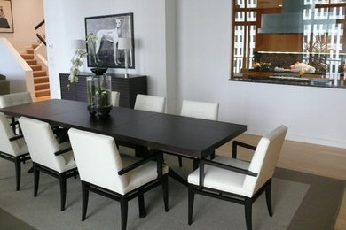 Réalisation d'une salle à manger design avec un mur blanc et un sol en bois brun.