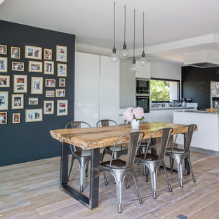 Idées déco pour une grand salle à manger ouverte sur la cuisine contemporaine avec un sol en bois clair, un mur noir et aucune cheminée.