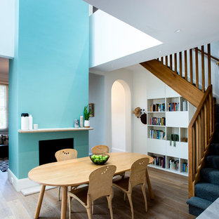 Inspiration for a contemporary dining room in Sydney with a standard fireplace, white walls, medium hardwood floors and beige floor.
