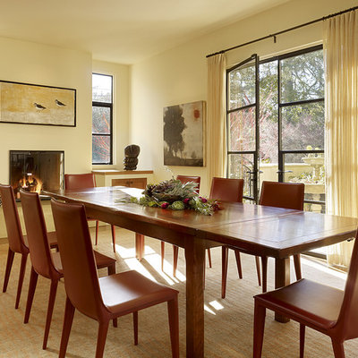 Example of a trendy dining room design in San Francisco with beige walls and a standard fireplace