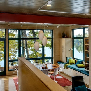 Immagine di una sala da pranzo minimal con pavimento in legno massello medio e stufa a legna