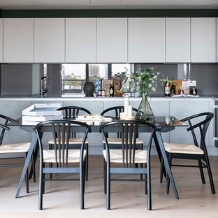 Contemporary kitchen/dining room in London with green walls, light hardwood flooring and beige floors.