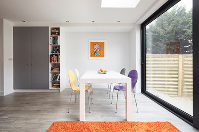This is an example of a medium sized contemporary enclosed dining room in London with white walls and grey floors.